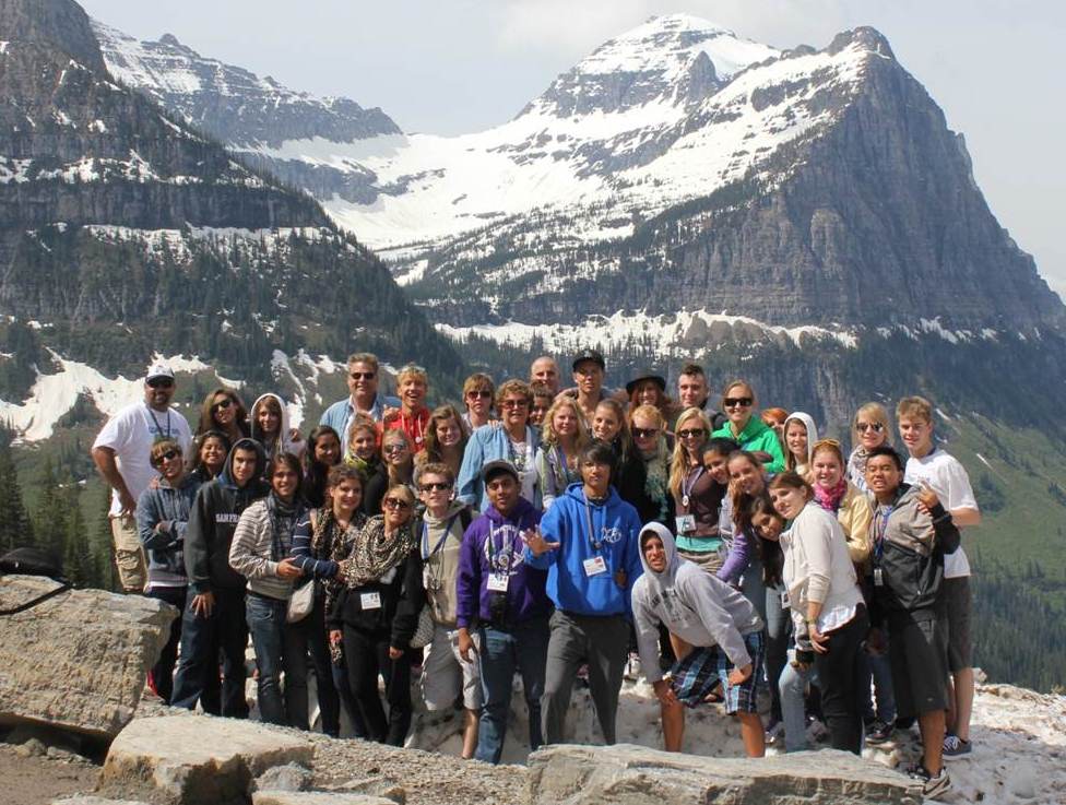 Tour group standing on the Continental Divide with mountains in the background.